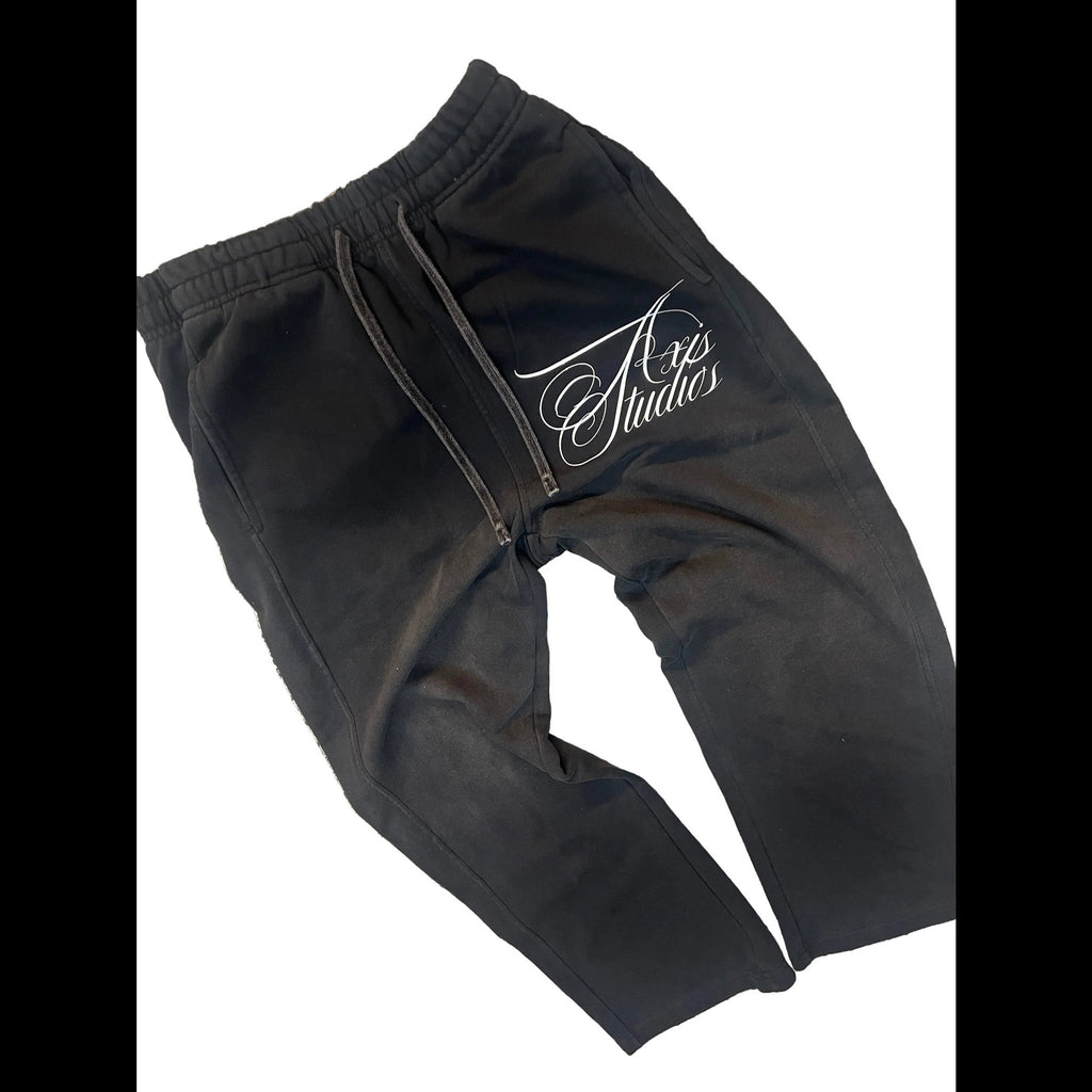 Black zip-up sweatpants with an elastic waistband and a white cursive logo on the left leg, displayed on a white background.