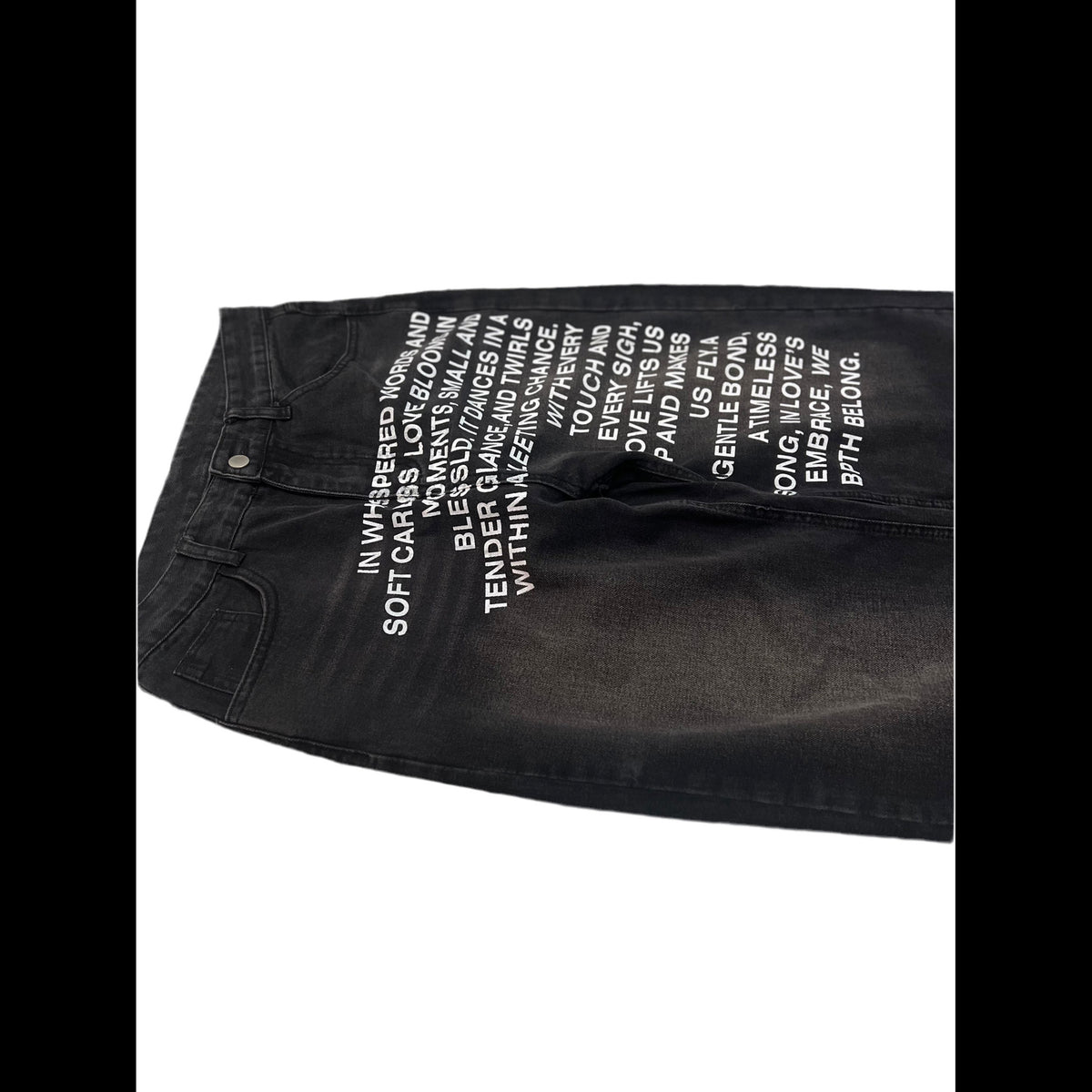 Black denim jeans with white printed text on the front, laid flat on a white background.