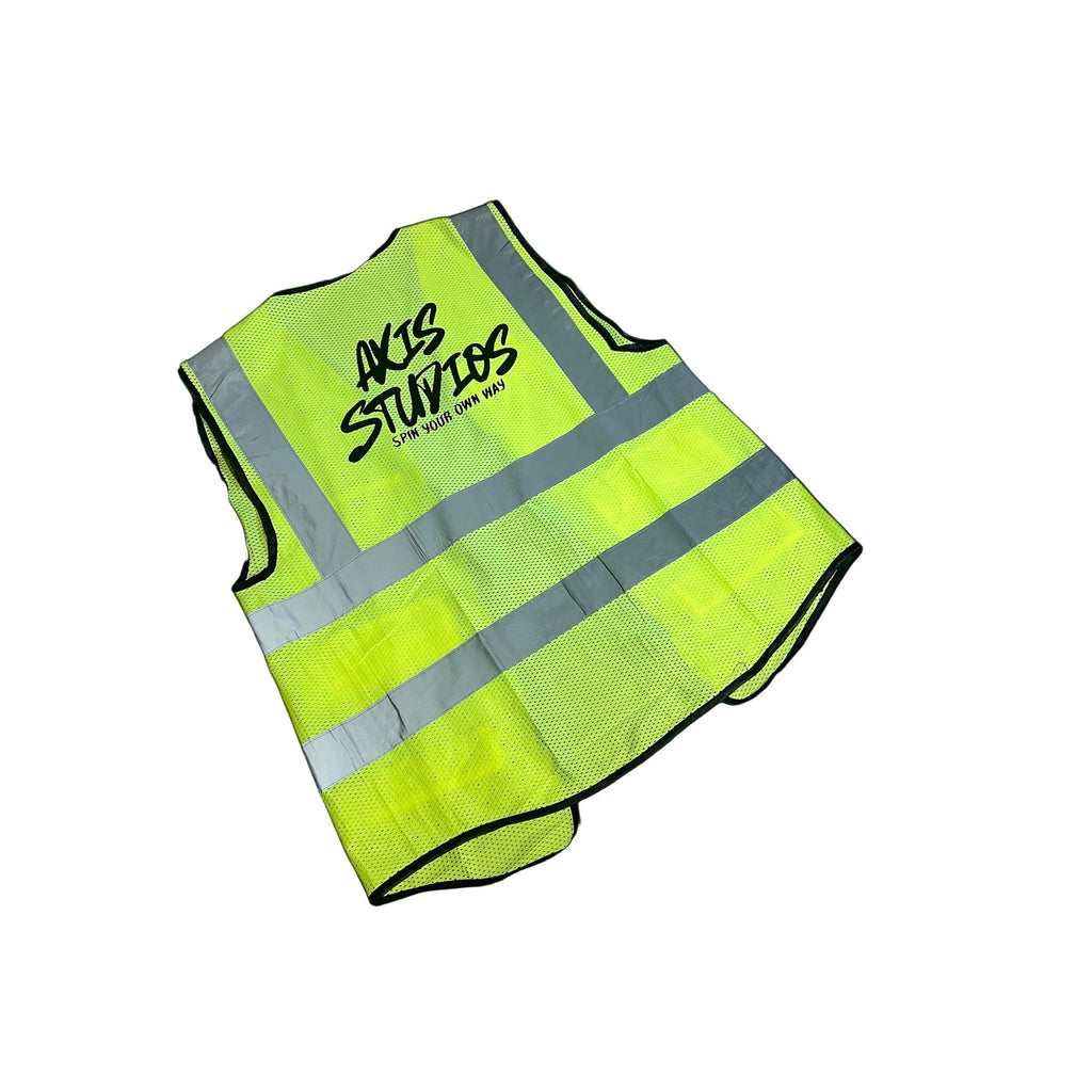 A high-visibility neon yellow safety vest with reflective silver stripes and black trim, featuring the text 'AKS STUDIOS' printed on the back, shown on a plain white background.