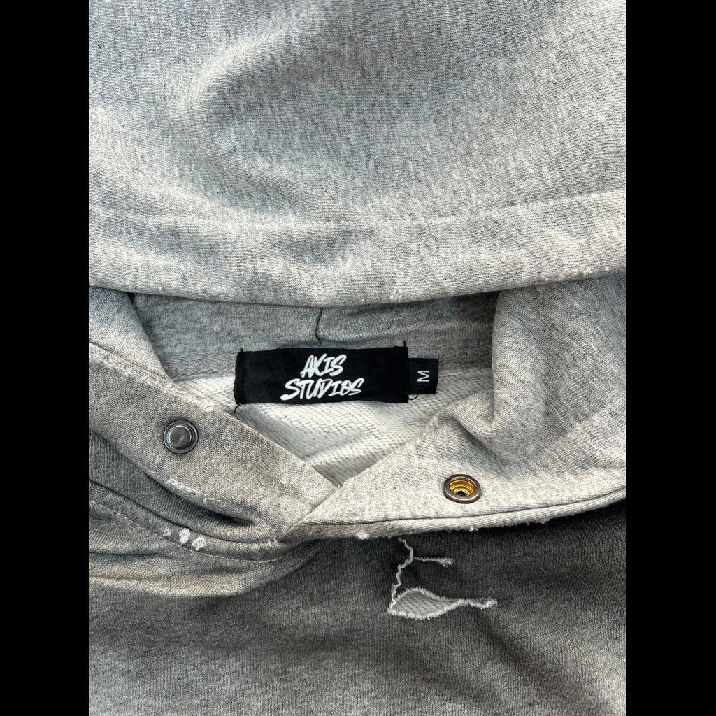 Close-up of a gray heather hoodie collar showing a black brand label that reads 'NOB STUPID' and 'M'.