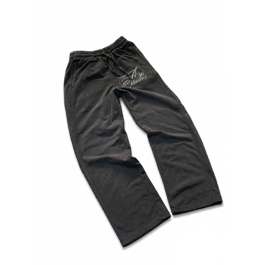 Black jogger sweatpants with a drawstring waist and a white cursive 'A V S Studios' logo on the upper left thigh, displayed flat against a white background with black letterbox borders.